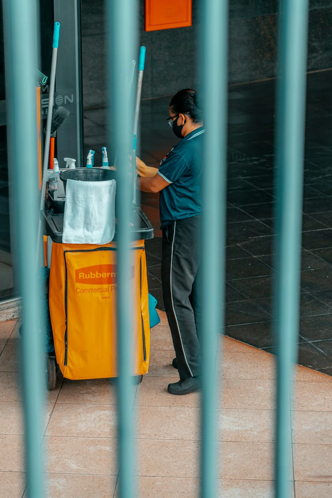 A man cleaning the outside glass roof from above with a tool in daylight.