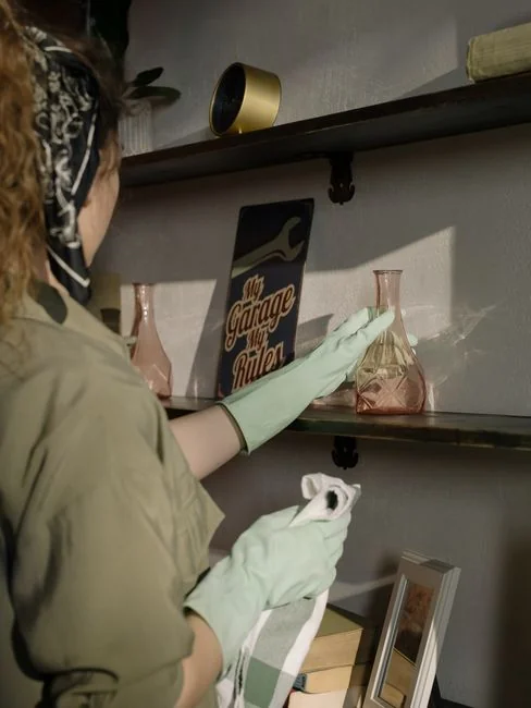 Close-up of hand cleaning window with squeegee outdoors using yellow gloves.